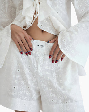 model wearing a white lace shirt  with a matching MYNE white shorts