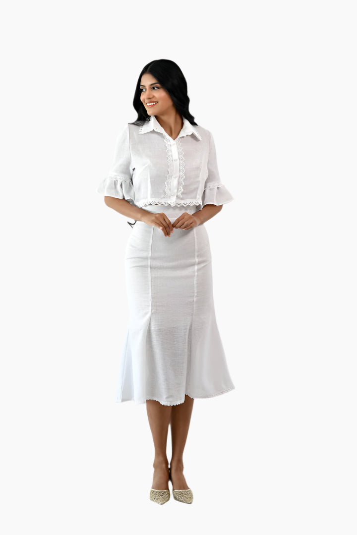 Woman wearing a white outfit, skirt soft mermaid flare just below the knee and ruffled white blouse