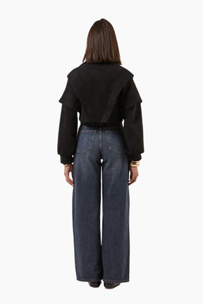 Person wearing a black jacket and blue jeans 