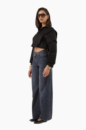 Woman wearing a black cropped jacket and blue jeans 