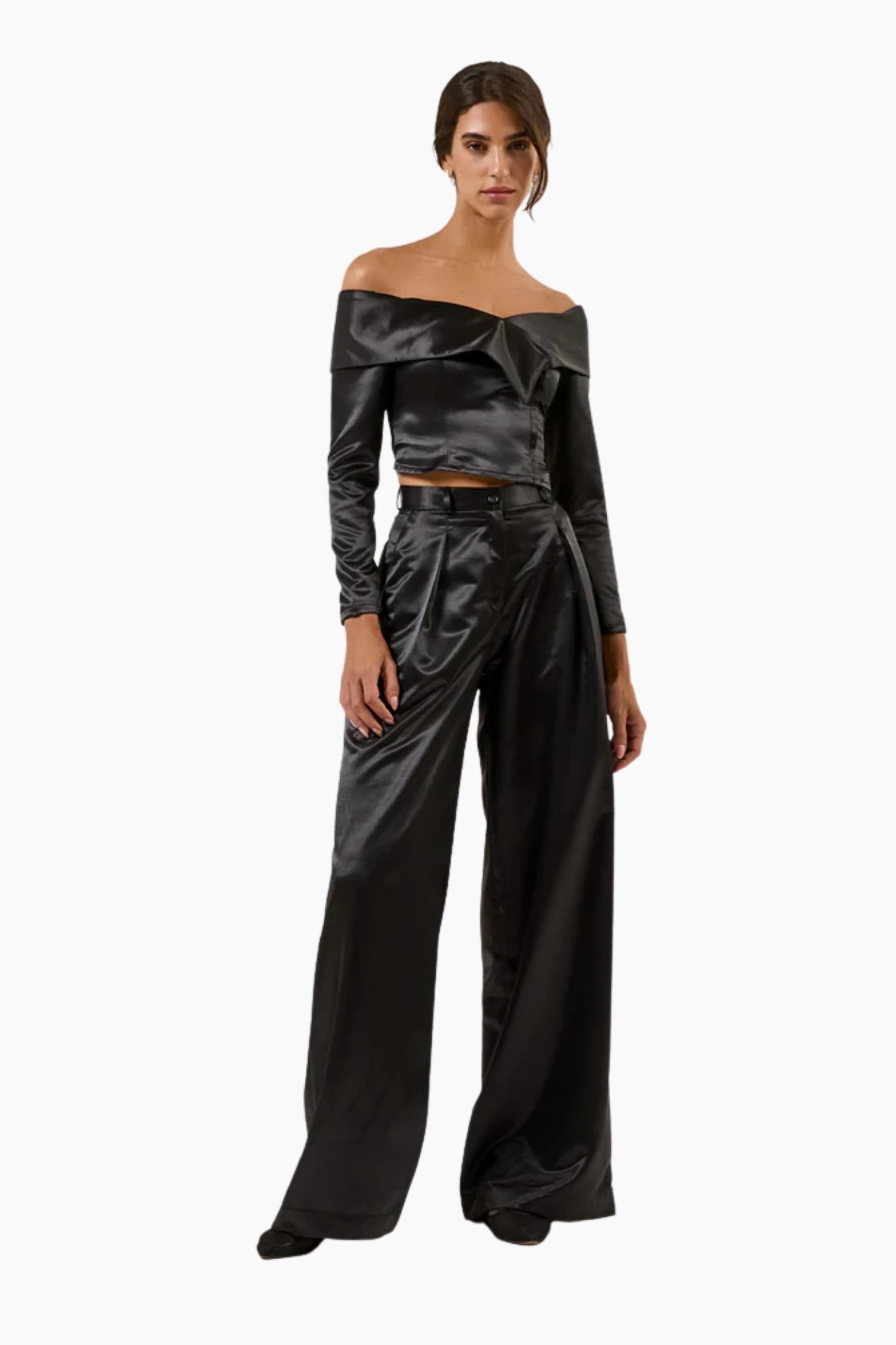 Woman wearing a black satin off-shoulder top and wide-leg pants on a white background