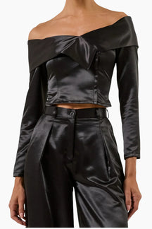 Black satin off-shoulder top and pants on a plain background