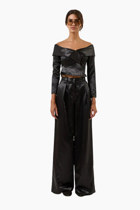 Woman wearing a black satin off-shoulder top and wide-leg pants