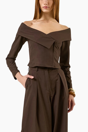model wearing an Off-shoulder double-breasted long-sleeves top with brown pants.
