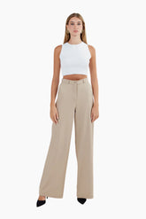 Woman wearing a white sleeveless top and beige high-waisted pants