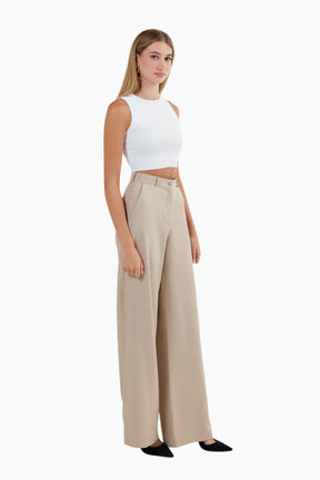 Woman wearing a white sleeveless top and beige wide-leg pants 