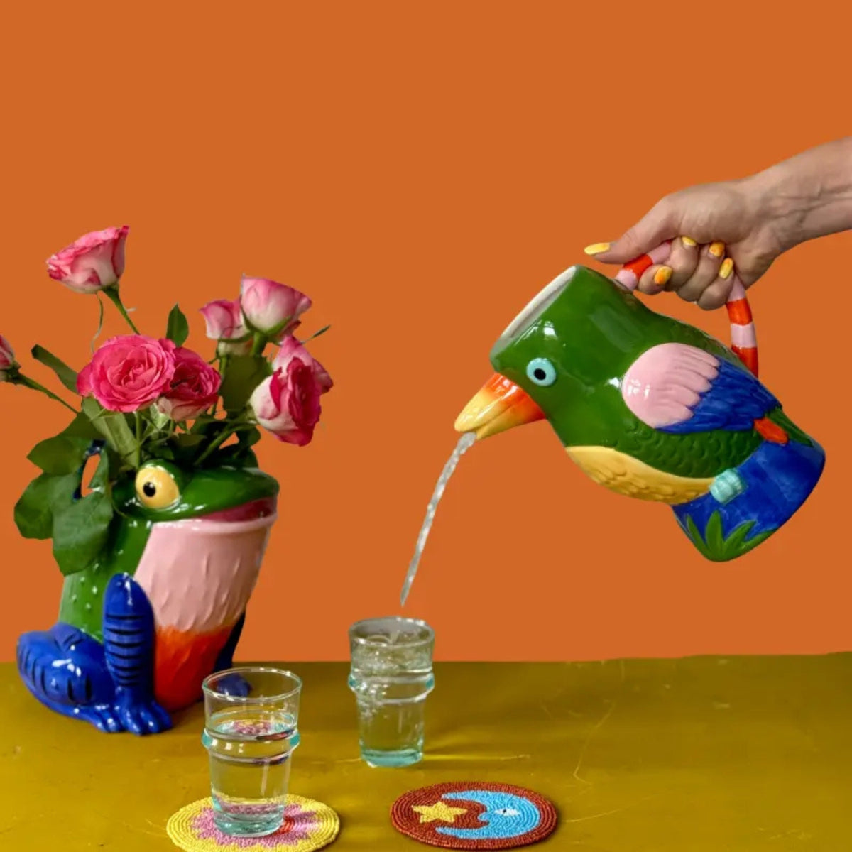 Bird-shaped ceramic pitcher pouring water into a glass