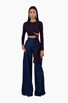 Woman wearing a dark long-sleeve top and blue high-waisted jeans on a white background