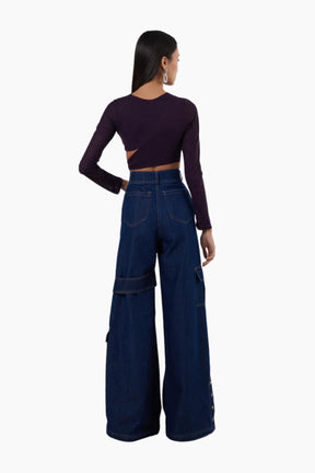 Person wearing a dark purple long-sleeve top and high-waisted blue jeans on a white background