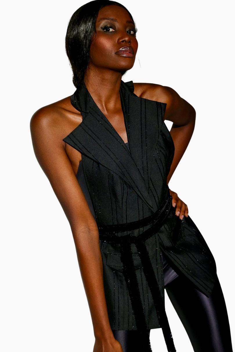 Woman wearing a black sleeveless top with a halter neck design 