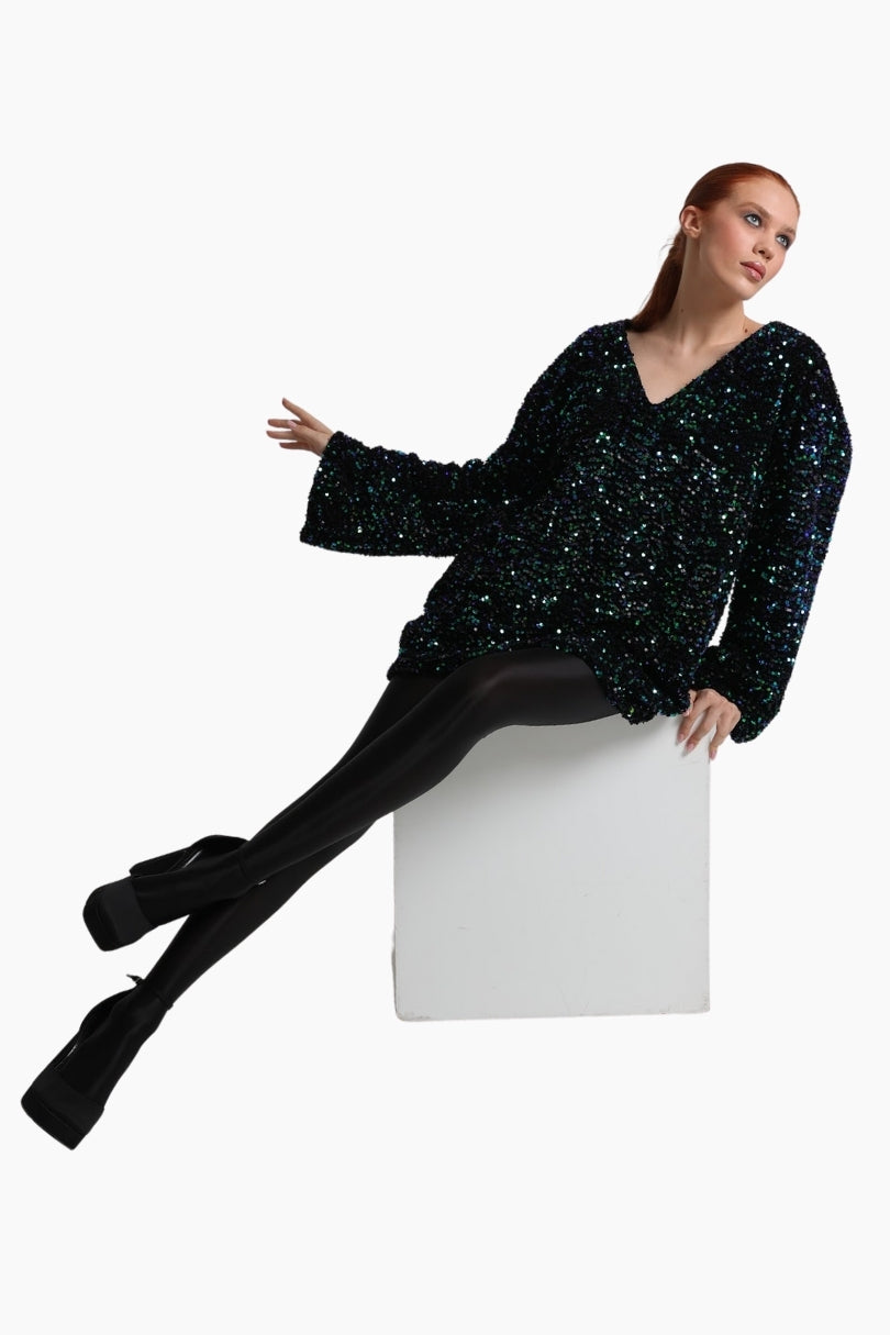 Woman wearing a black sequin top and black tights sitting 
