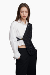 Woman wearing a white blouse and black floral vest 