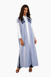 Woman wearing a light blue dress with floral embroidery on a white background