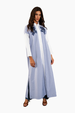 Woman wearing a light blue dress with floral embroidery on a white background