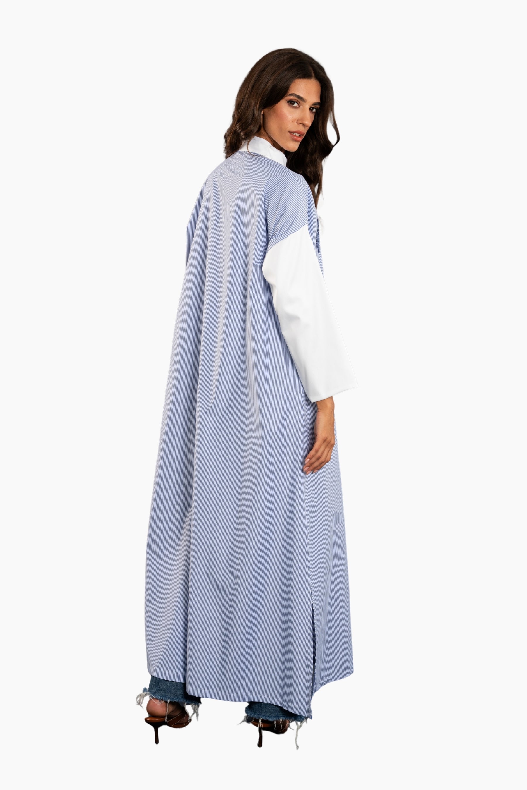 Woman wearing a light blue abaya over a white shirt on a white background