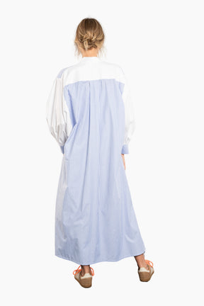 Woman wearing a light blue and white striped dress on a white background