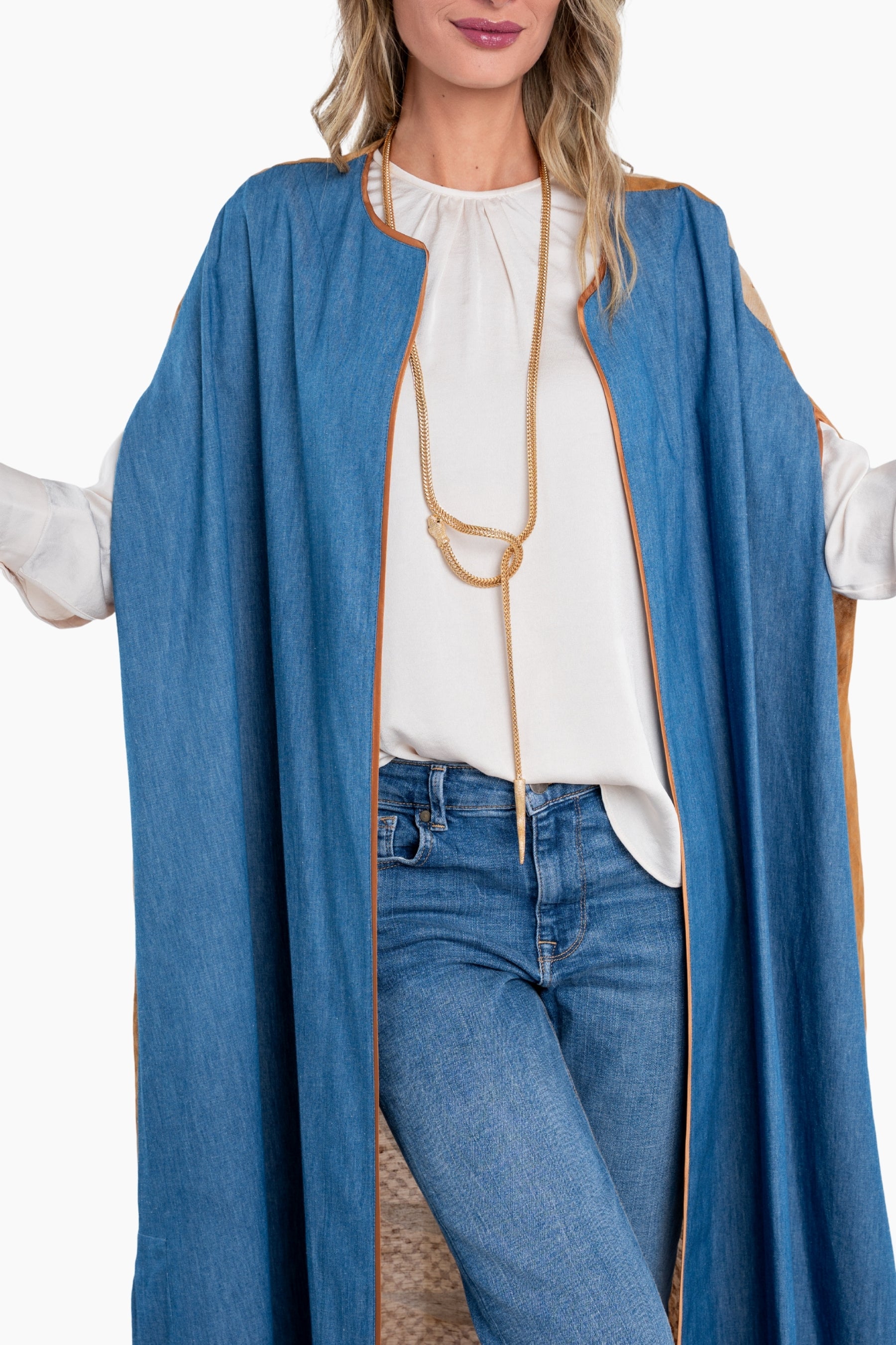 Woman wearing a long blue coat over a white blouse and jeans on a white background
