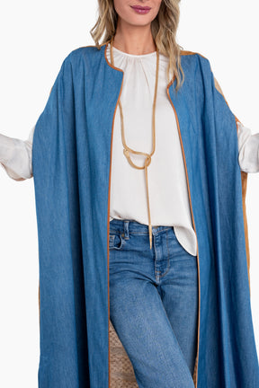 Woman wearing a long blue coat over a white blouse and jeans on a white background