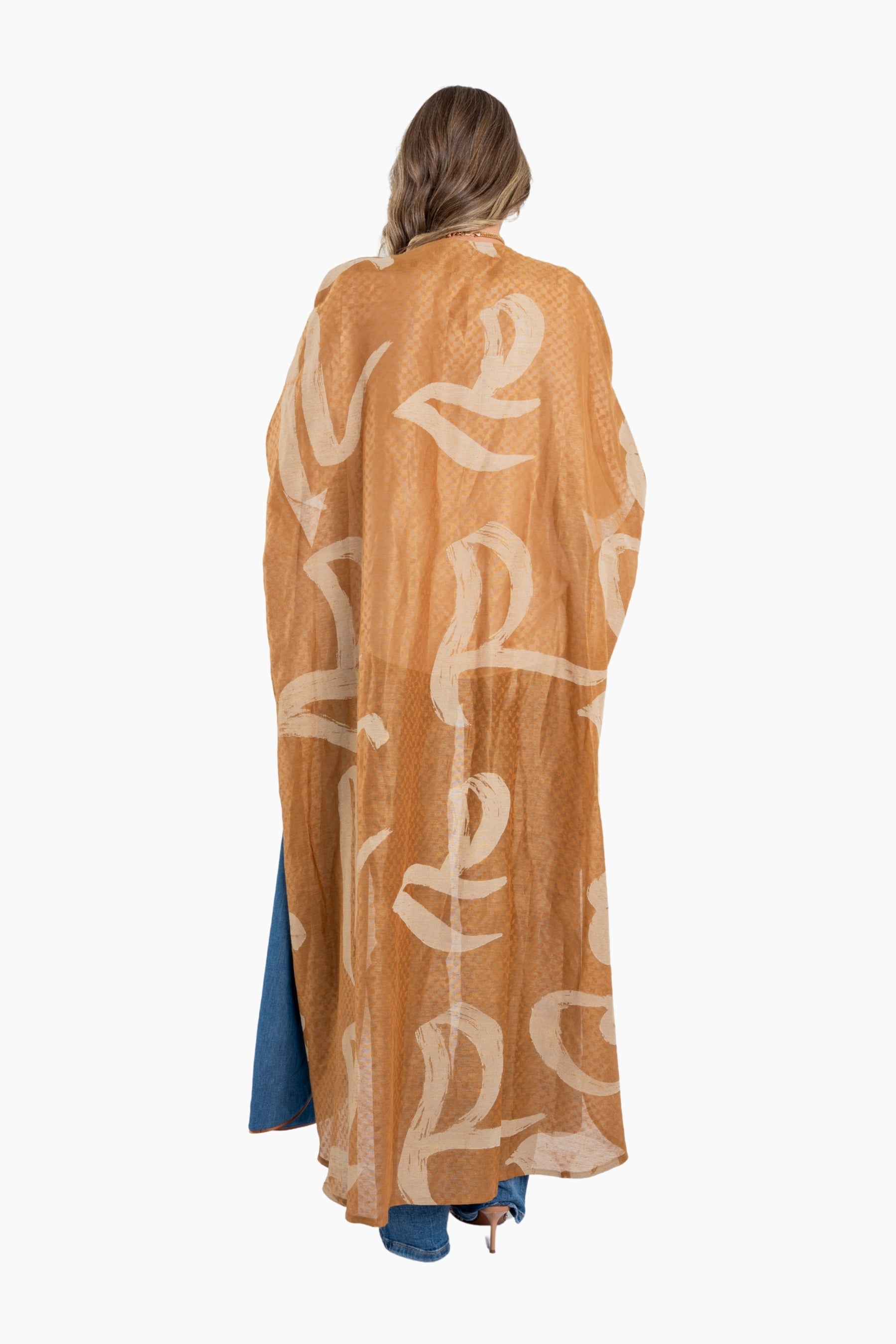 Woman wearing a long, light brown kimono-style garment with white lettering on a white background