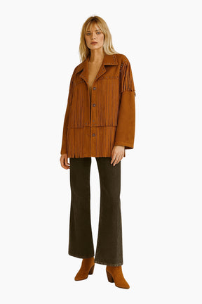 Woman wearing a brown fringed jacket and flared pants 