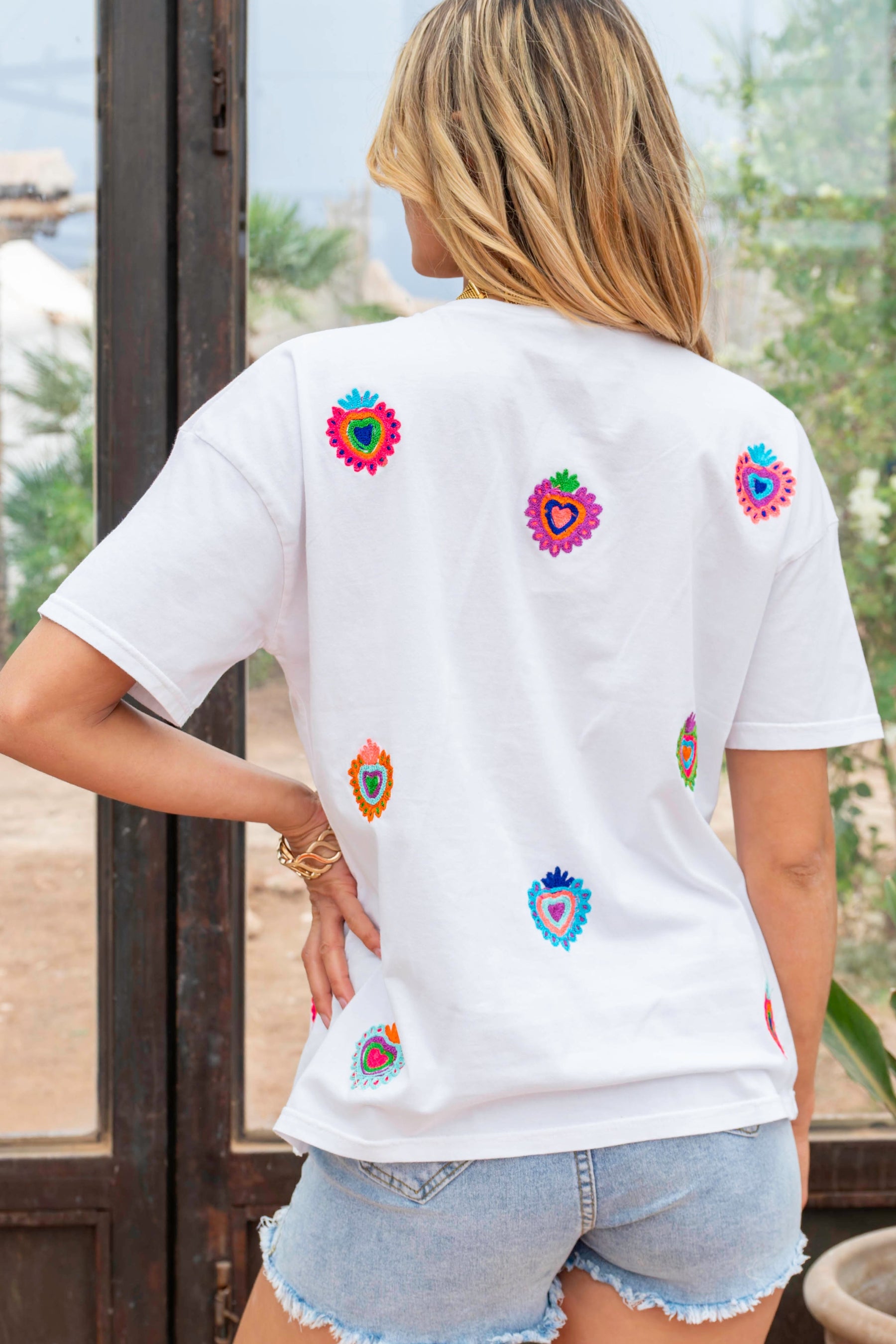 Person wearing a white t-shirt with colorful heart designs outdoors