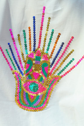 Colorful beaded hand design on a white fabric background
