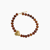 Necklace with heart-shaped brown beads and a gold pendant on a white background