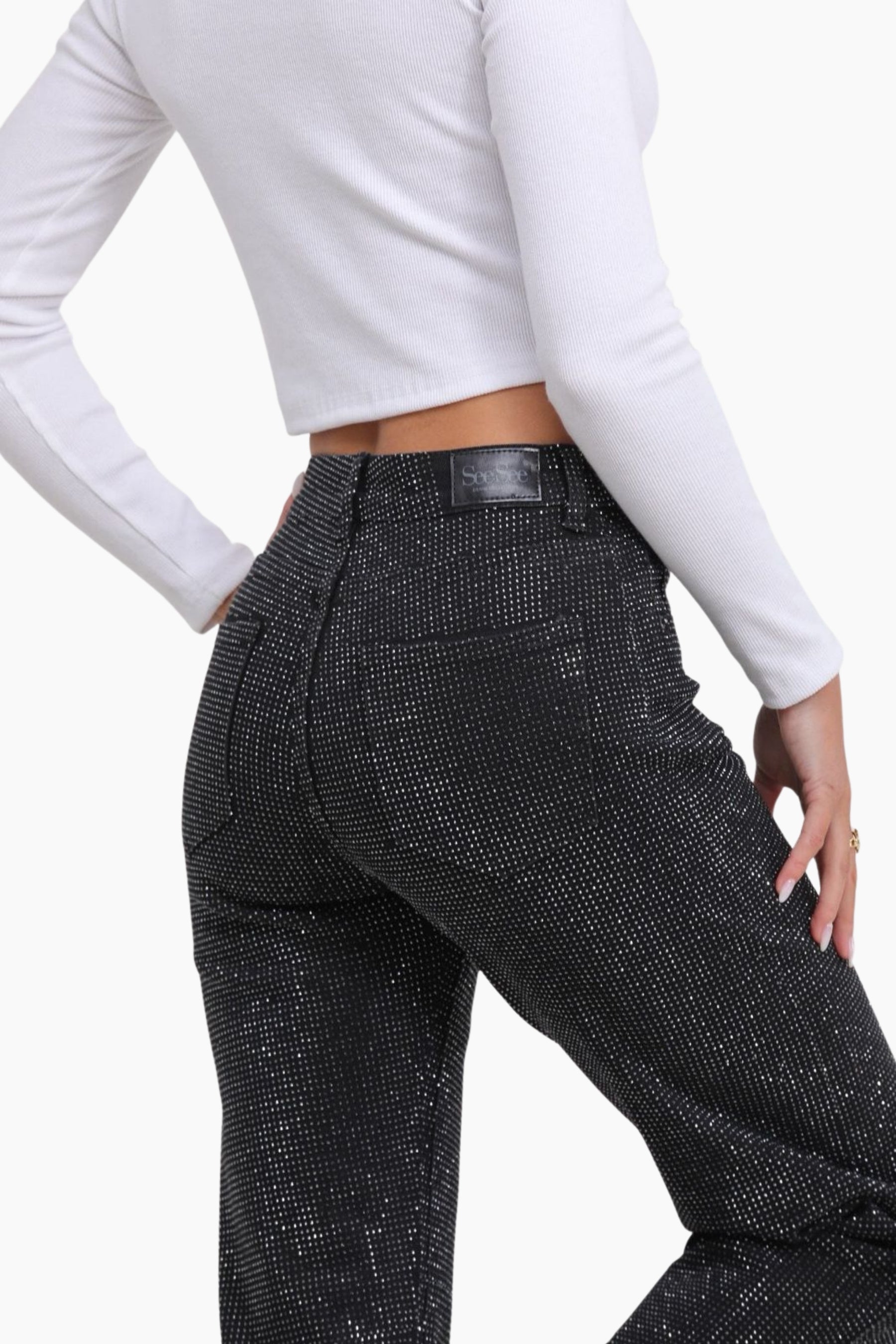 Person wearing black herringbone pants with a white long-sleeve top 