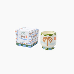Candle with palm tree design and matching packaging on a white background