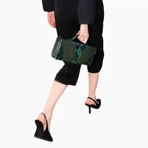 Person wearing a black outfit with a green clutch bag on a white background