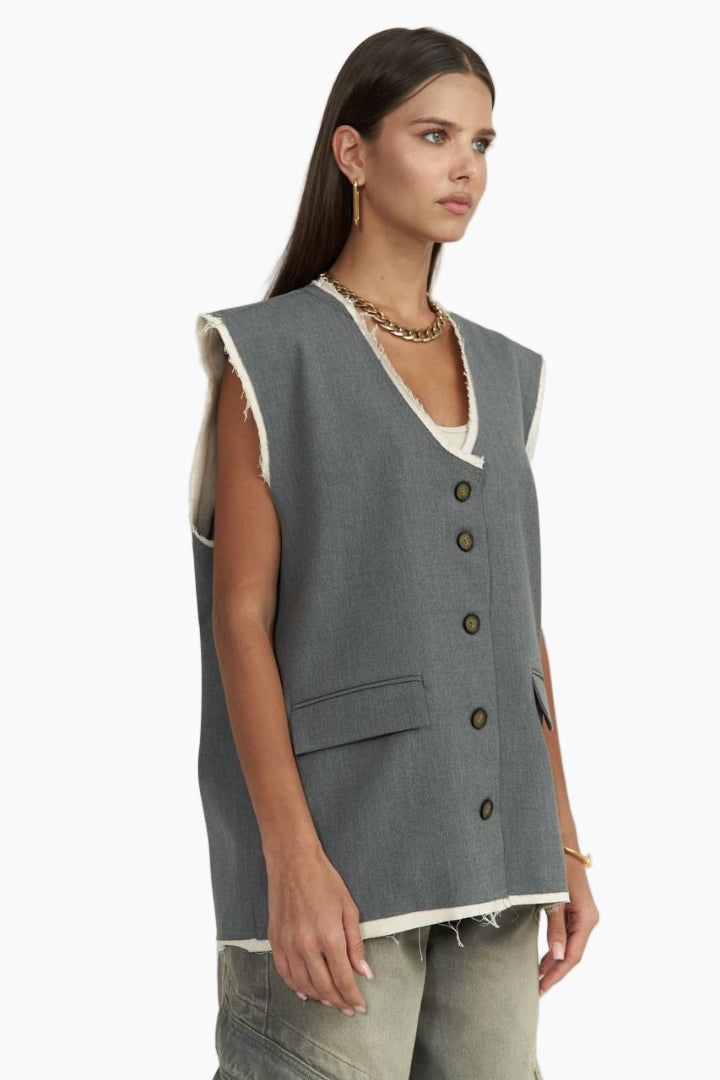 Woman wearing a gray sleeveless vest with buttons on a white background