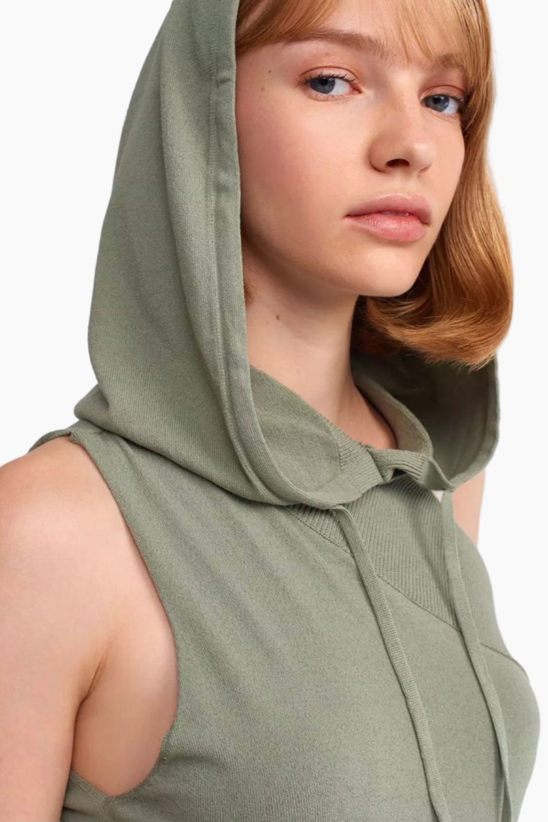 Woman wearing a green sleeveless hoodie against a white background