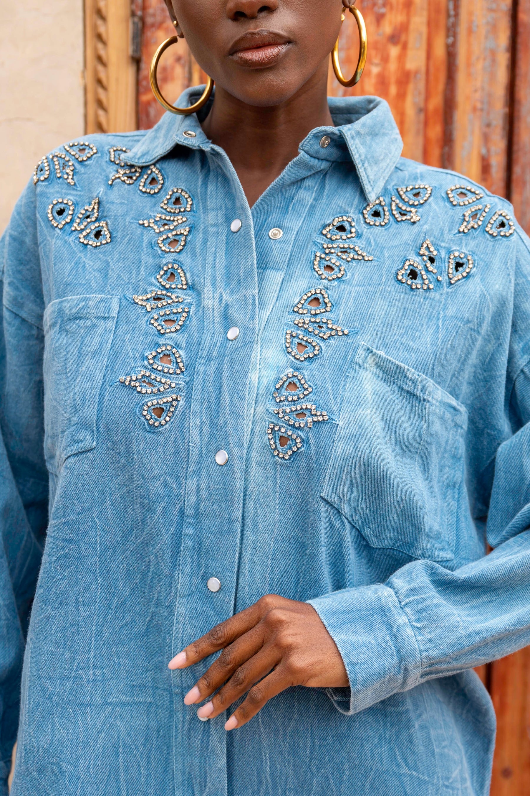 Blue denim shirt with intricate beadwork on a wooden background