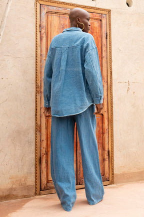 Person wearing a blue outfit standing in front of a wooden door.