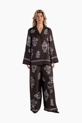Woman wearing a dark brown pajama set with white patterns on a white background