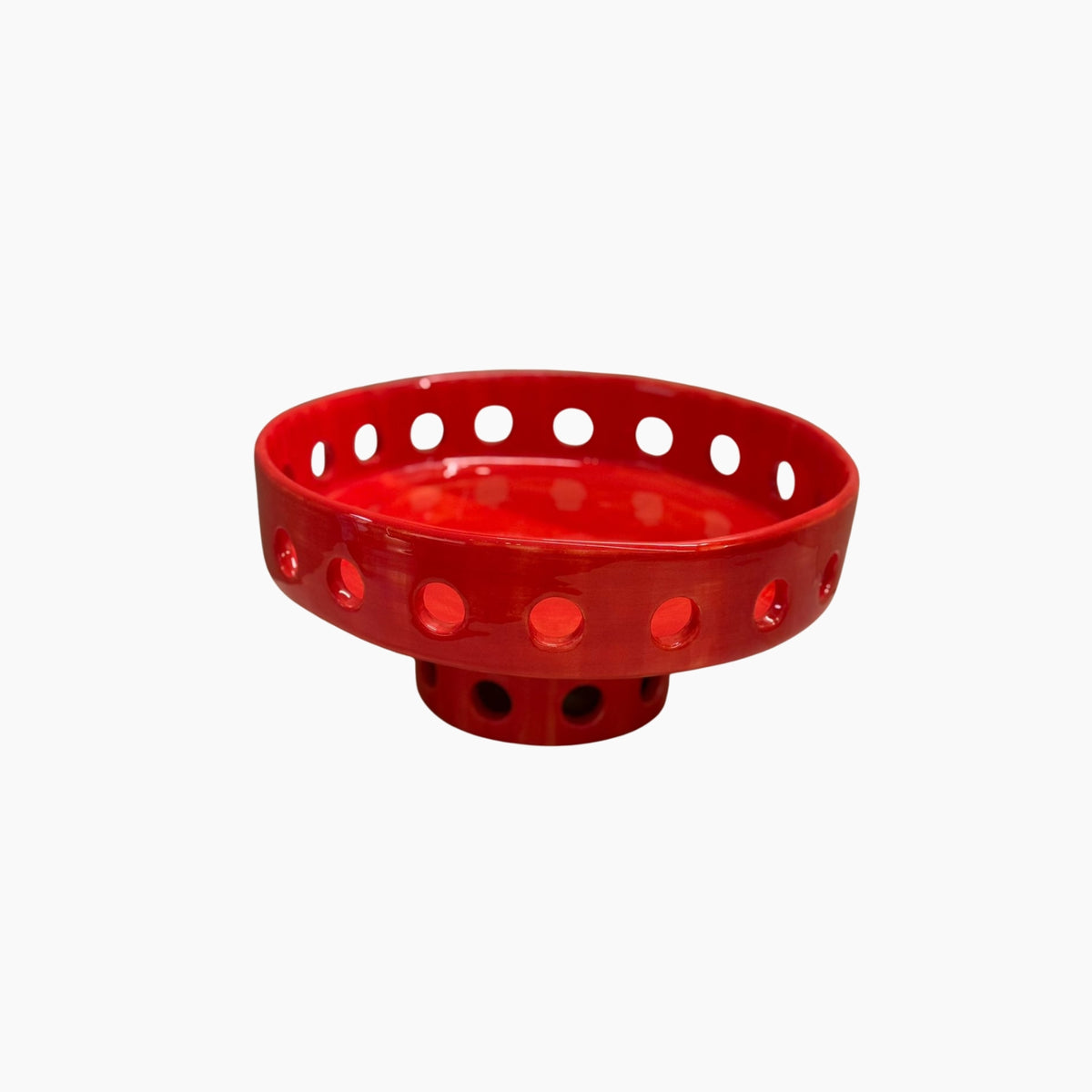 Red plastic bird feeder with holes on a white background