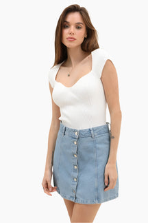 Woman wearing a white sleeveless top and denim skirt 