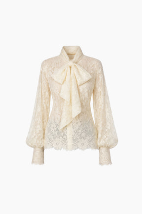 Cream-colored lace blouse with a bow detail on a white background