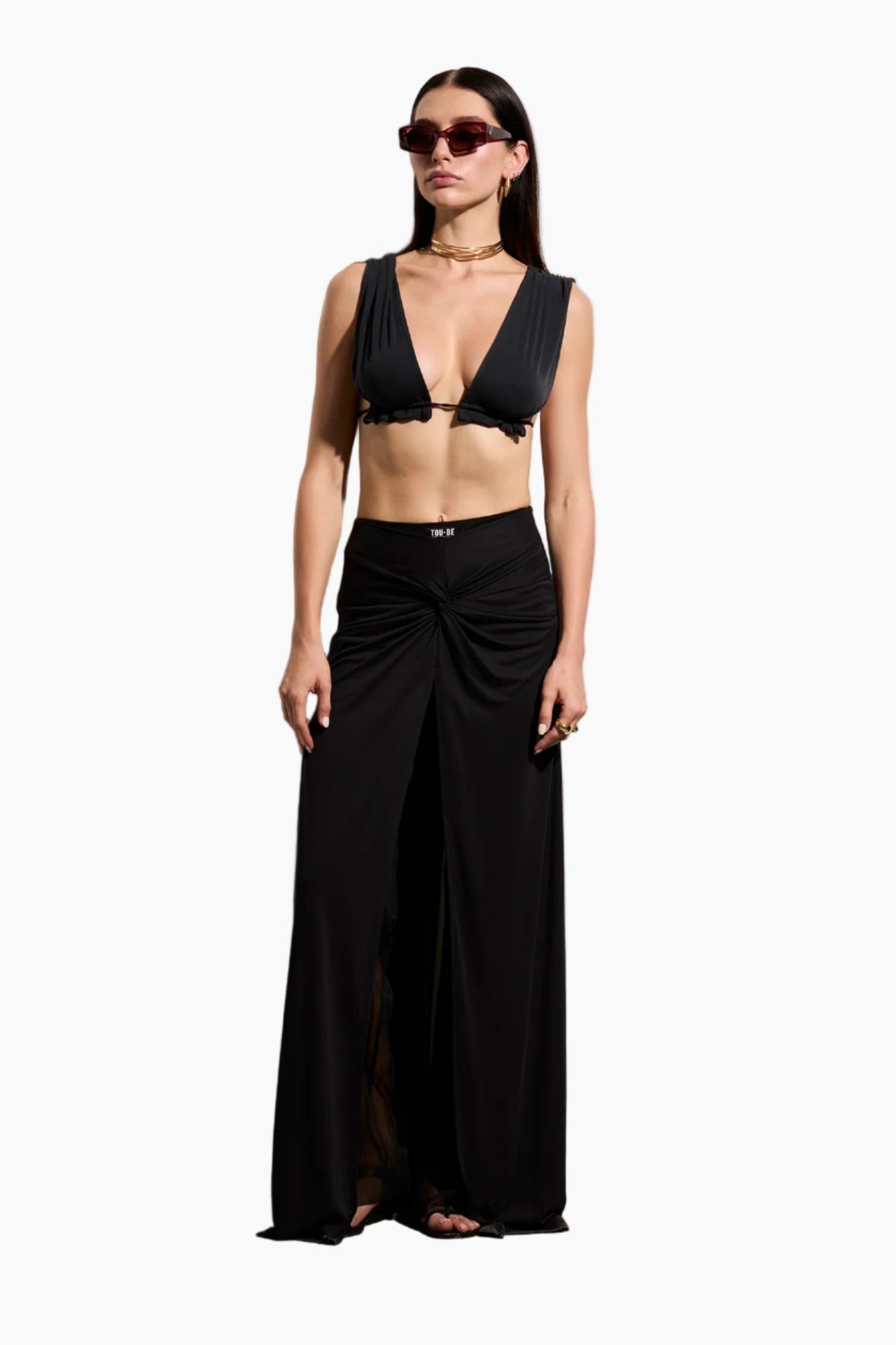 Woman wearing a black outfit with a deep neckline and flowing supreme pants featuring a mesh inner layer .