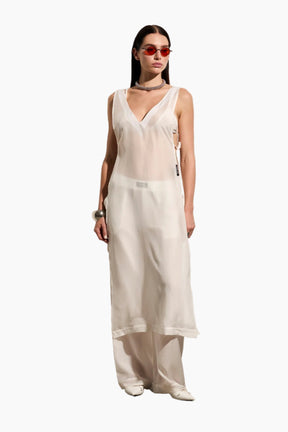 Woman wearing a white sleeveless top and pants.