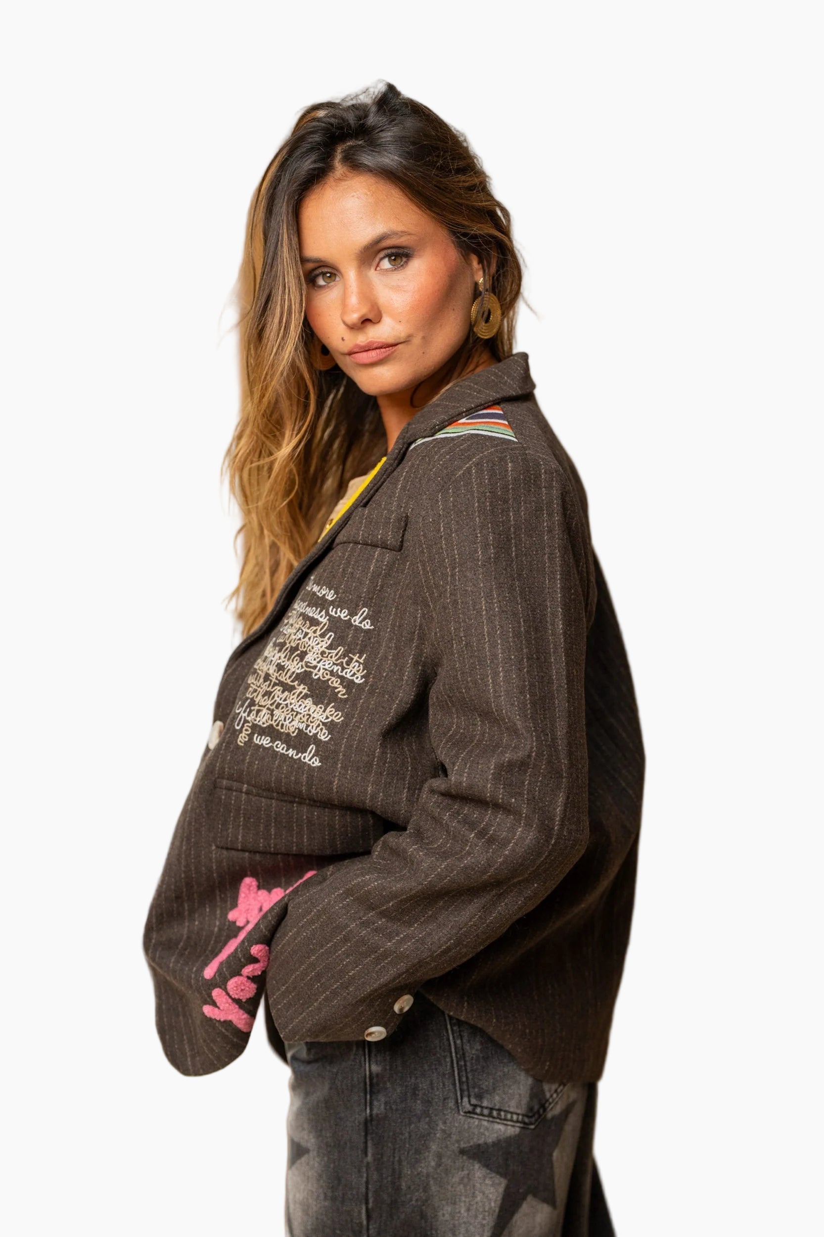 Woman wearing a brown jacket with text and pink design