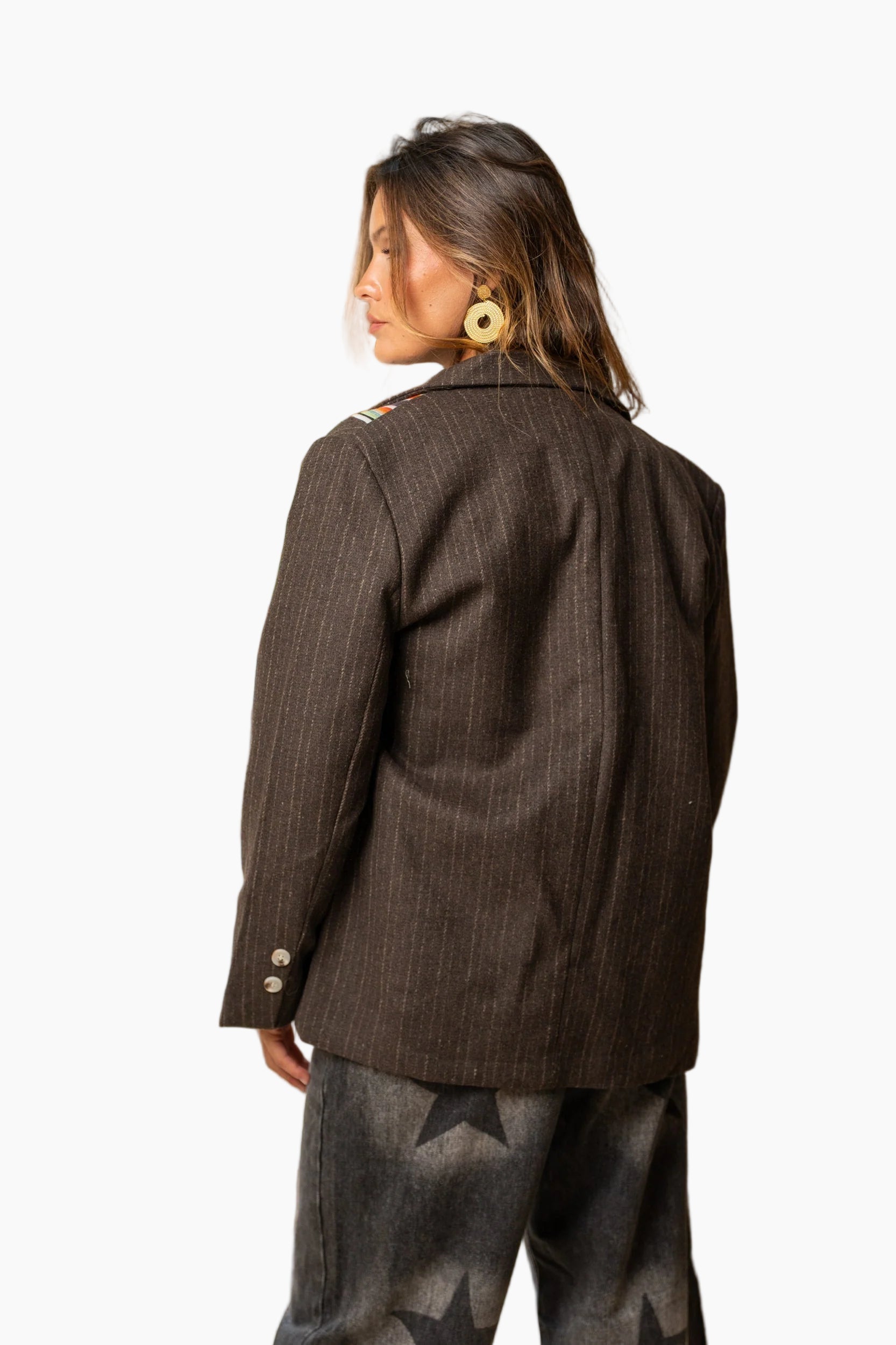 Woman wearing a brown pinstripe jacket and patterned pants